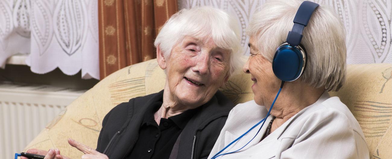 Two older women smiling with headphones