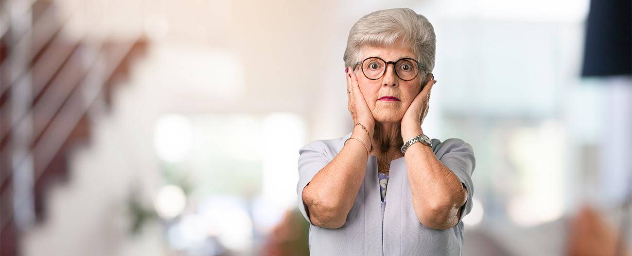 Older woman with hands over ears due to noise