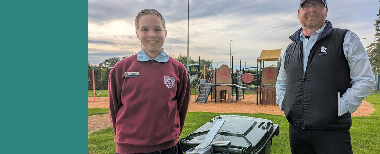 Man and girl standing next to bin in a park