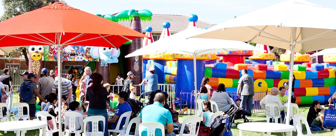 families at public festival around a big jumping castle