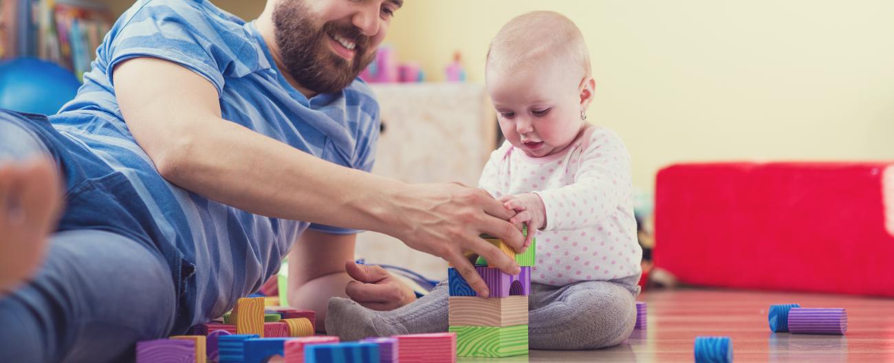 Father playing with young baby on floor