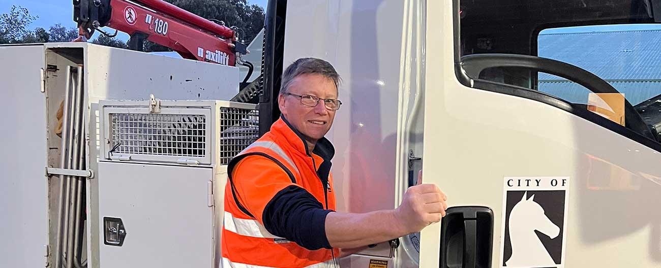 Man in orange high-vis vest climbing into truck 